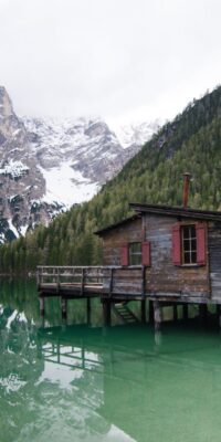 brown wooden house o lake near snow covered mountain